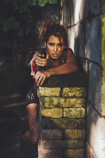 Schöne junge ernsthafte Frauen-Spezialeinheiten, die eine Waffe halten und sich auf den Angriff in verlassenen Ruinen vorbereiten.