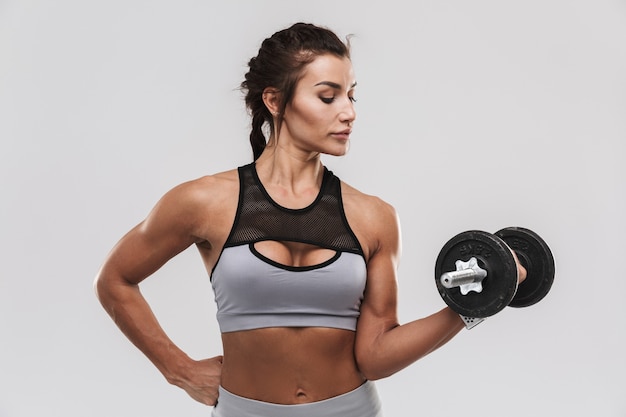 Schöne junge erstaunliche starke Sport-Fitness-Frau, die isoliert über weißem Wandhintergrund posiert, machen Übungen mit Hantel.