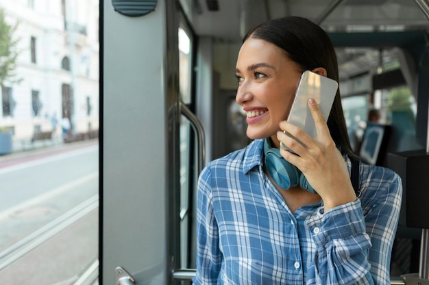 Schöne junge europäische Frau sitzt in öffentlichen Verkehrsmitteln und spricht glücklich am Handy