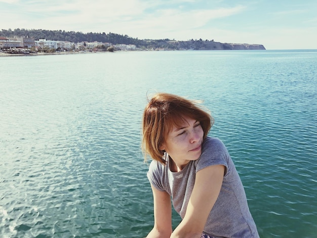 Foto schöne junge frau am meer gegen den himmel