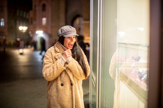 Schöne junge Frau am Schaufenster zur Weihnachtszeit