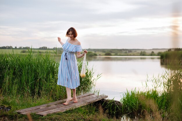 Schöne junge Frau am See bei Sonnenuntergang