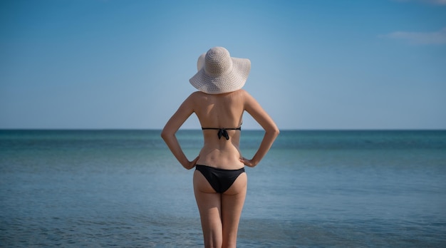 Schöne junge Frau am Strand mit Hut