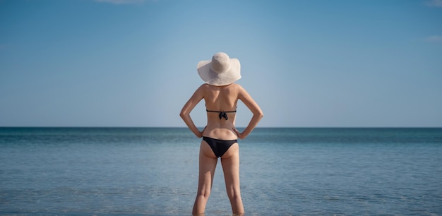 Schöne junge Frau am Strand mit Hut