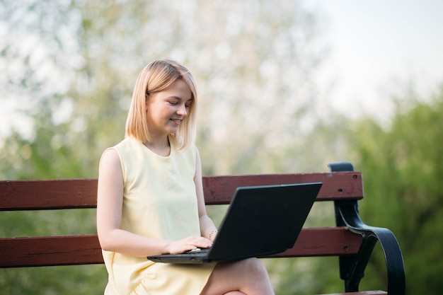 schöne junge Frau arbeitet am Laptop im Park Mädchen Freiberuflerin in der Natur