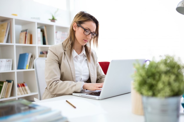 Schöne junge Frau arbeitet mit Laptop in ihrem Büro.