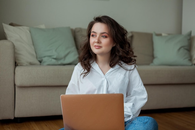 Schöne junge Frau arbeitet online zu Hause mit einem Laptop Home Office Online studieren Soziale Medien Videogespräch Gemütliches Haus