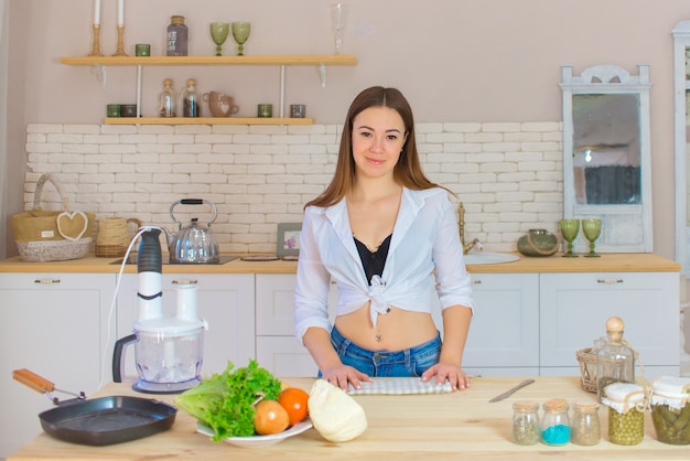 Schöne junge Frau bereitet Gemüsesalat in der Küche vor. Gesundes Essen. Veganer Salat. Diät. Diät-Konzept. Gesunder Lebensstil. Zu Hause kochen. Essen zubereiten. Zutaten auf dem Tisch schneiden