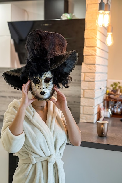 Schöne junge Frau bereitet sich auf den Karneval vor und probiert eine weiße mysteriöse venezianische Maske an