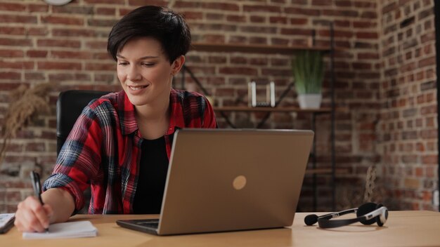 Schöne junge Frau, die am Laptop arbeitet