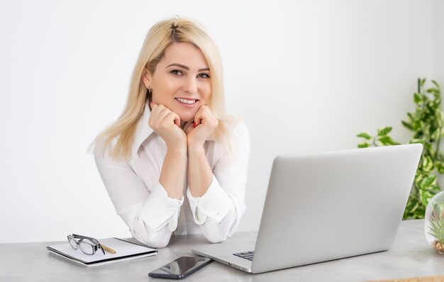 Schöne junge Frau, die an ihrem Laptop in ihrem Büro arbeitet.