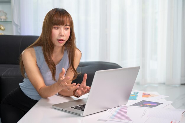 Schöne junge Frau, die an Laptop-Computer arbeitet Online-Meeting von zu Hause aus