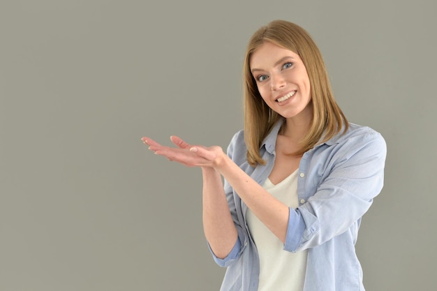 Schöne junge Frau, die auf grauem Hintergrund aufwirft