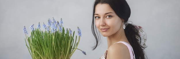 Schöne junge Frau, die Blumenstrauß von Frühlingsblumen hält, die die Kamera sinnlich romantisch betrachtet