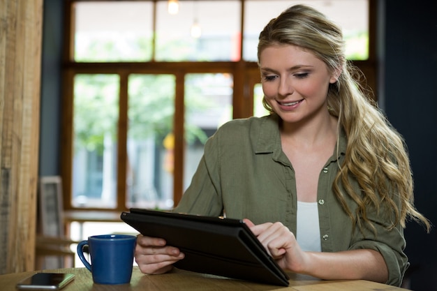 Schöne junge Frau, die digitales Tablett im Café verwendet