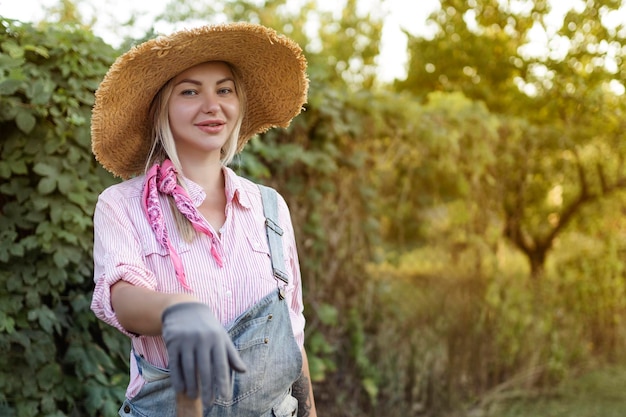 Schöne junge Frau, die draußen in der Sommernatur im Garten arbeitet