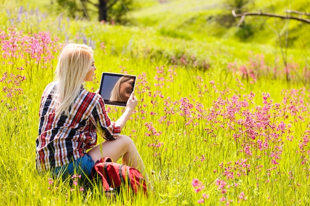 Schöne junge Frau, die draußen Tablet-Computer auf Gebirgshintergrund verwendet.