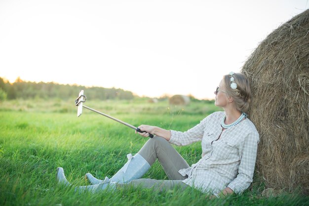 Schöne junge Frau, die ein Selfie auf dem Gras auf der Wiese macht