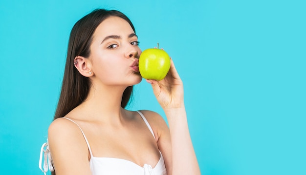 Schöne junge Frau, die einen Apfel isst.