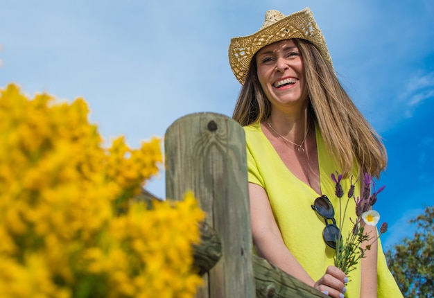 Schöne junge Frau, die einen Frühlingstag genießt. Frau glücklich und lächelnd trägt sie einen Cowboyhut.