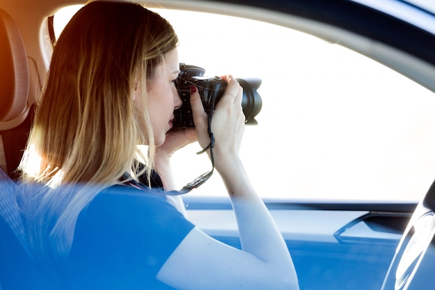 Schöne junge Frau, die Fotos vom Auto macht.