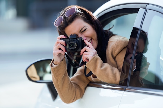 Foto schöne junge frau, die fotos vom auto macht