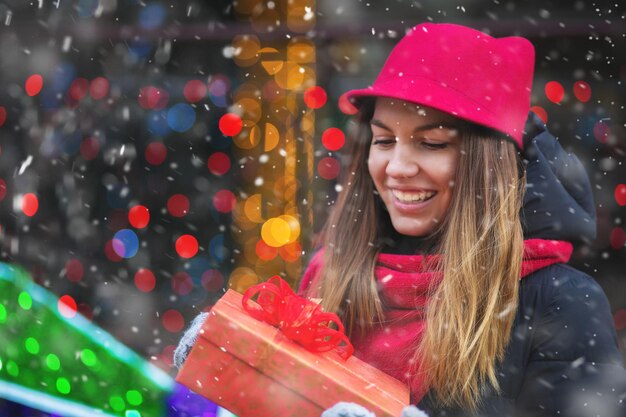 Schöne junge Frau, die Geschenk auf der Straße gegen verzierte Vitrine empfängt