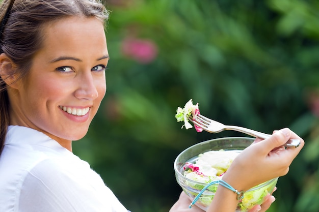 Schöne junge Frau, die grünen Salat, draußen hält