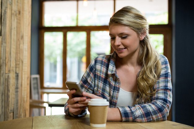 Schöne junge Frau, die Handy im Café verwendet