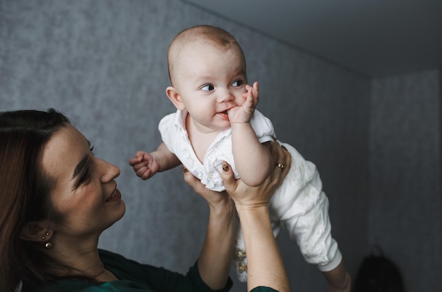 Schöne junge Frau, die ihr süßes kleines Baby hält und hochhebt Konzept des Familienglücks