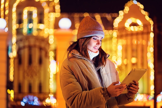 Schöne junge Frau, die ihre digitale Tablette im Winter verwendet