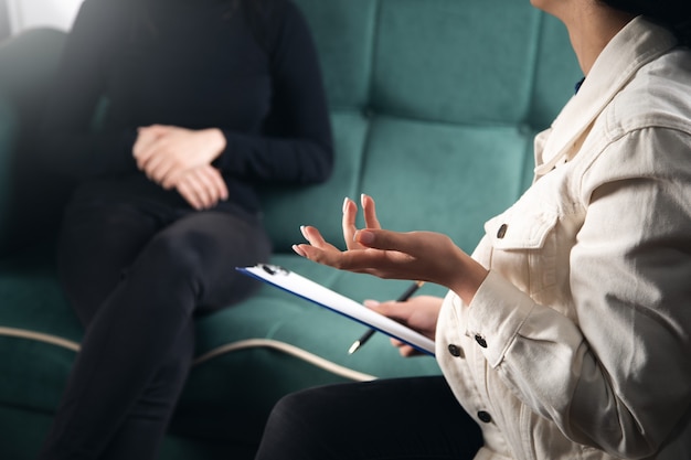 Foto schöne junge frau, die ihre probleme mit der psychologin bespricht