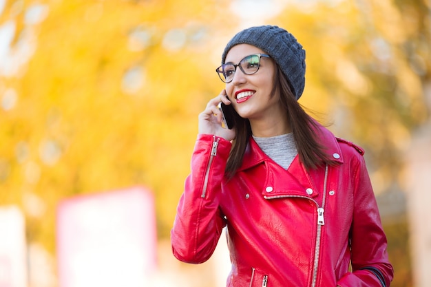 Schöne junge Frau, die ihren Handy in der Stadt verwendet.