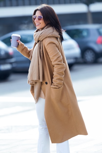 Schöne junge Frau, die ihren Handy in der Straße verwendet.