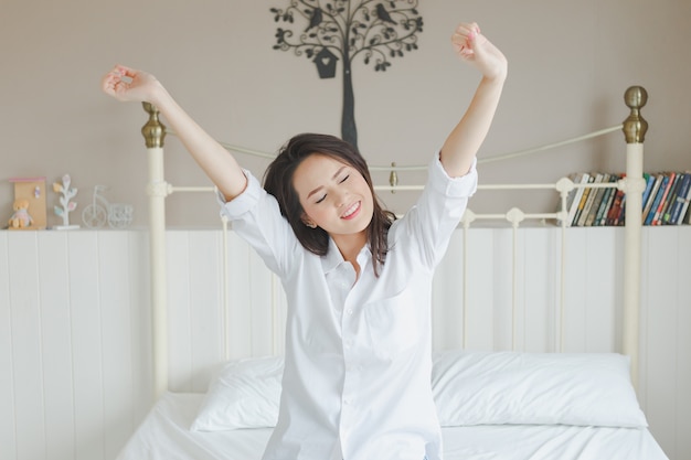 schöne junge Frau, die im Bett aufwacht