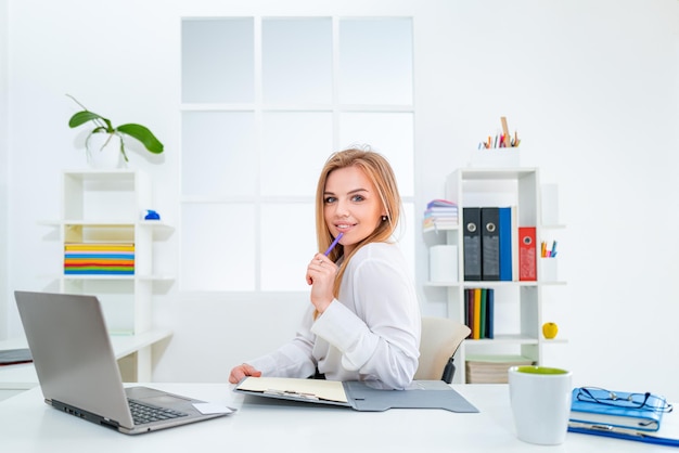 Schöne junge Frau, die im Büro arbeitet Glückliche Geschäftsfrau oder Sekretärin der Geschäftsleute mit Notizbuch im Büro