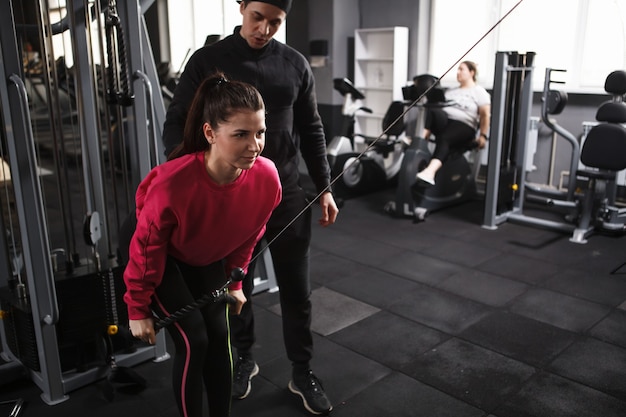 Schöne junge Frau, die im Crossover-Gymnastikgerät ausübt