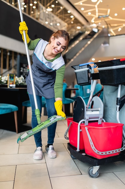 Schöne junge Frau, die im Einkaufszentrum putzt. Reinigungskonzept.