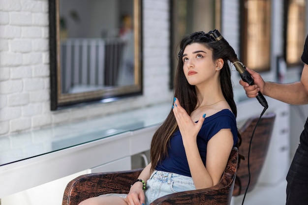 Schöne junge Frau, die im Friseursalon sitzt und nach oben schaut Foto in hoher Qualität