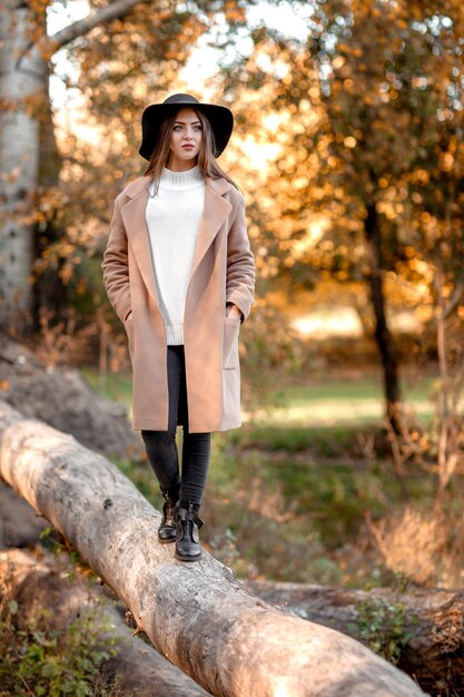 Schöne junge Frau, die im Herbst im Park aufwirft