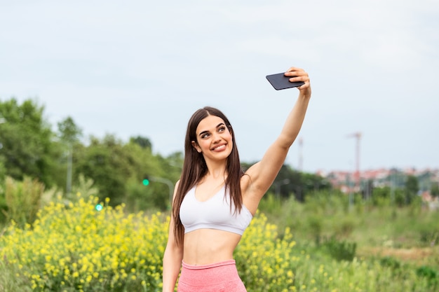 Schöne junge Frau, die im Stadtrennen läuft, das ein selfie nimmt