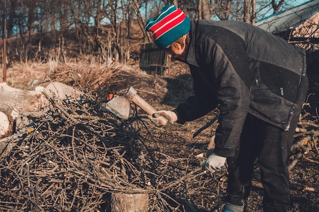 Schöne junge Frau, die im Winter im Dorf Brennholz mit einer Axt hackt, um das Haus zu heizen