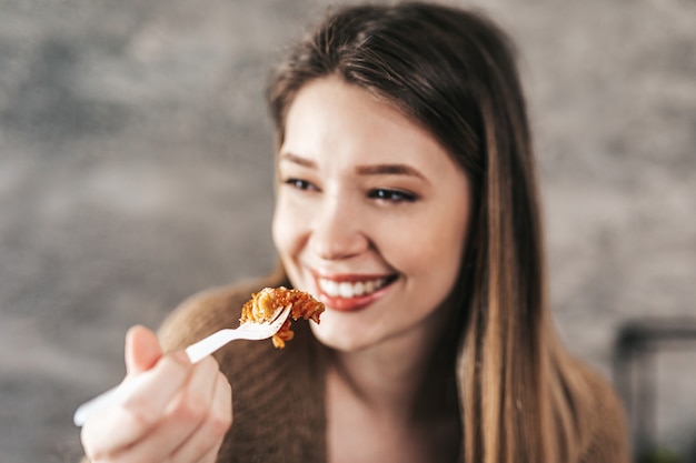 Schöne junge Frau, die italienische Teigwaren isst.