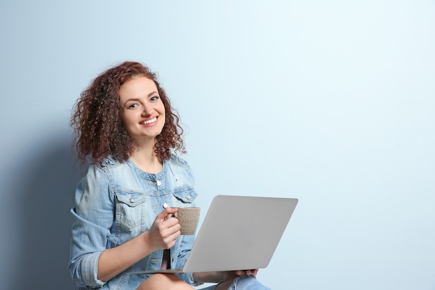 Schöne junge Frau, die Laptop auf Lichtwand verwendet