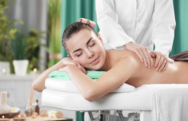 Schöne junge Frau, die mit Handmassage am Schönheits-Spa entspannt