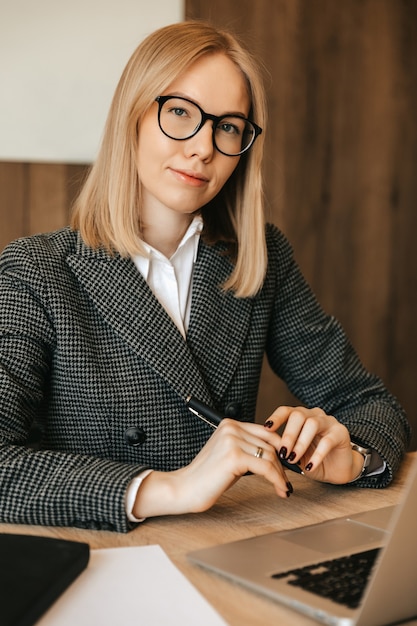 Schöne junge Frau, die mit Laptop-Computer arbeitet, konzentriert und ernst, guter verantwortlicher Büroangestellter.