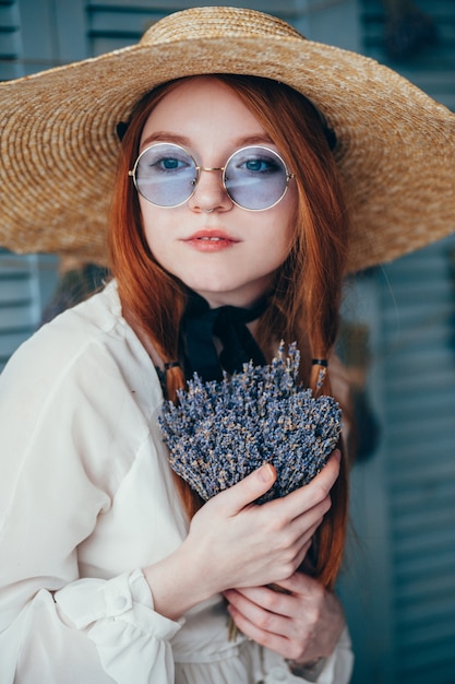 Schöne junge Frau, die mit Lavendel gegen die blaue Wand sitzt.