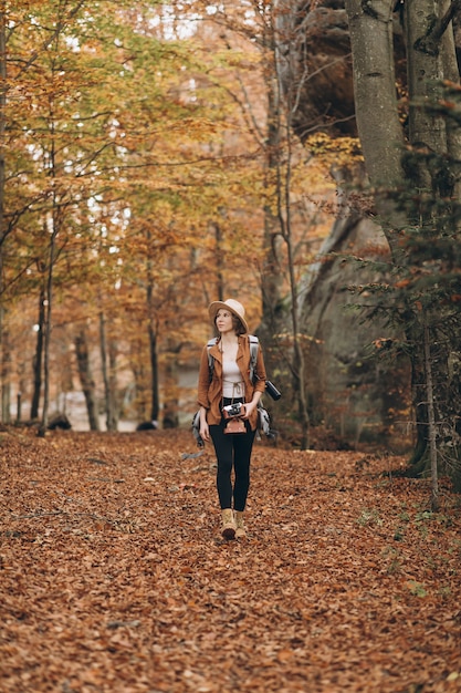 Schöne junge Frau, die reizend Herbstwald geht