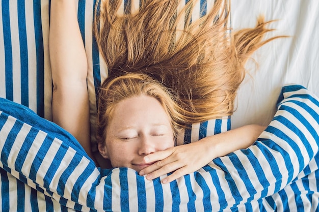 Schöne junge Frau, die sich im Bett hinlegt und schläft. Bekomme nicht genug Schlafkonzept