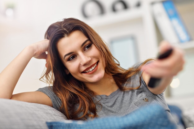 schöne junge frau, die sich zu hause vor dem fernsehen entspannt